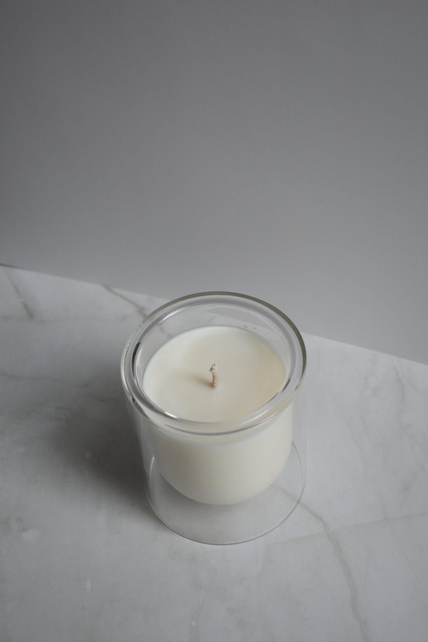White candle in a glass holder on a marble surface