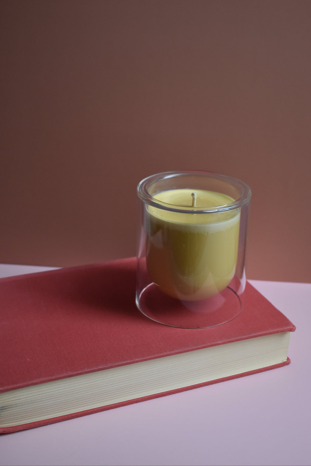Small glass container with a yellow candle on a red book