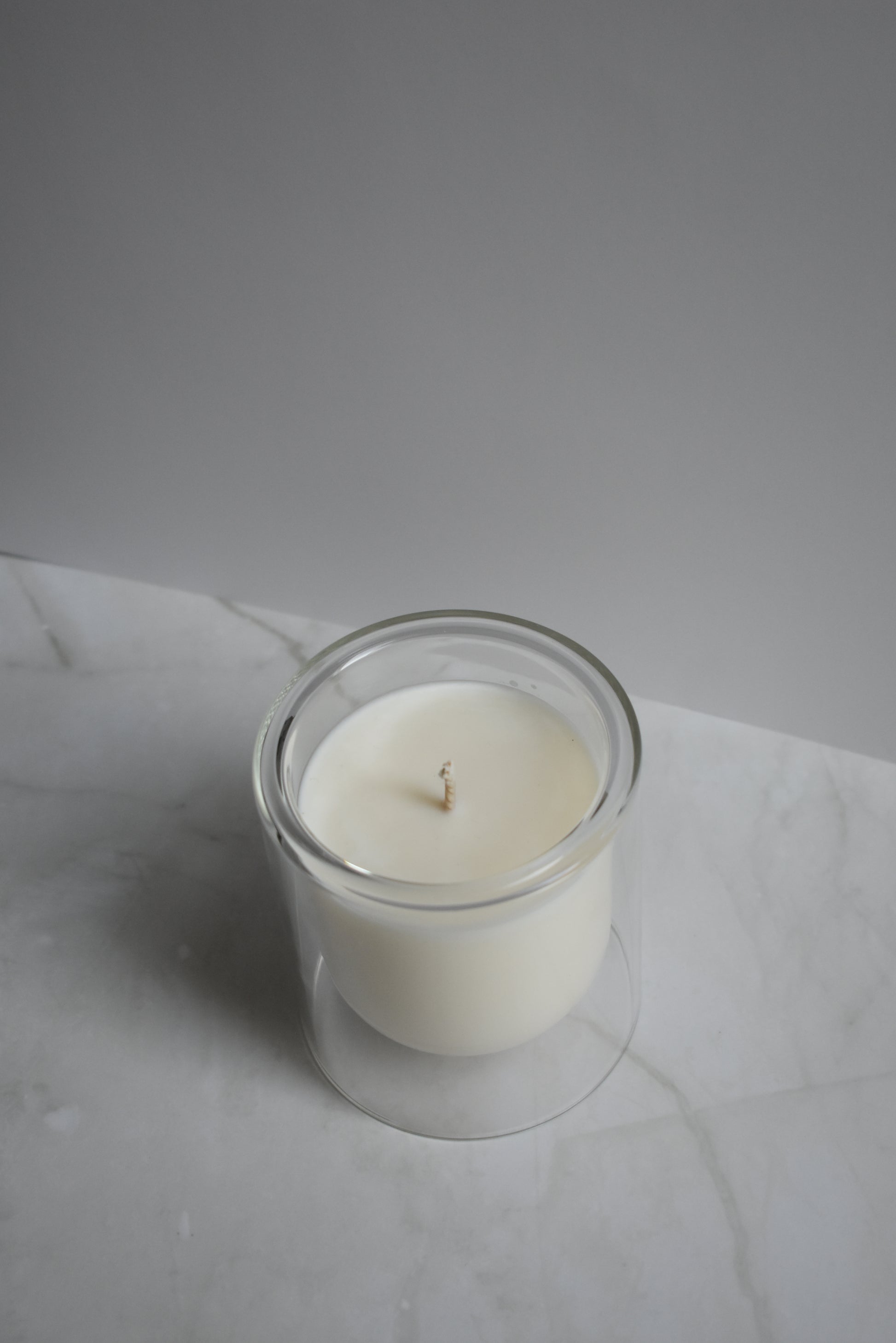 White candle in a glass holder on a marble surface